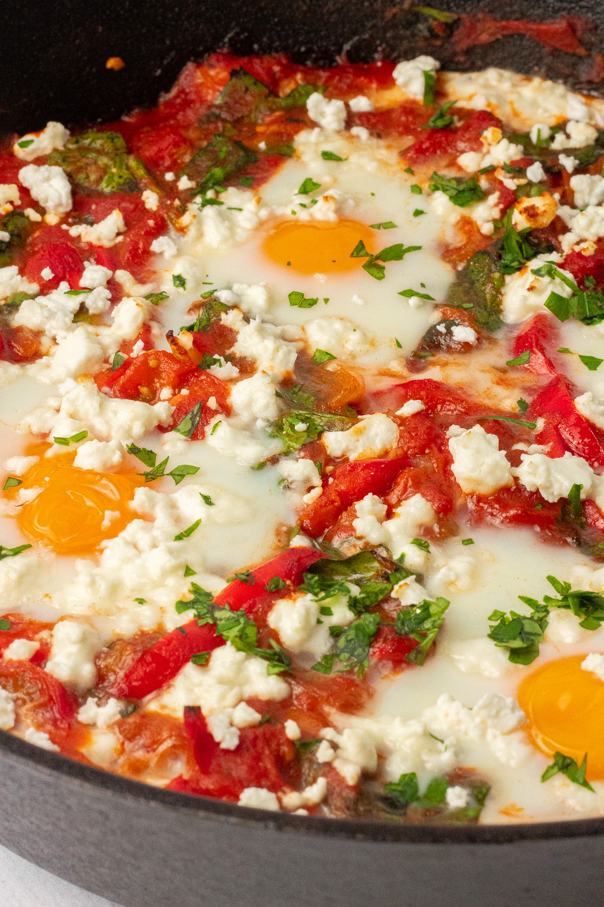 A close view of shakshuka in a cast iron skillet, also called "eggs in purgatory". 