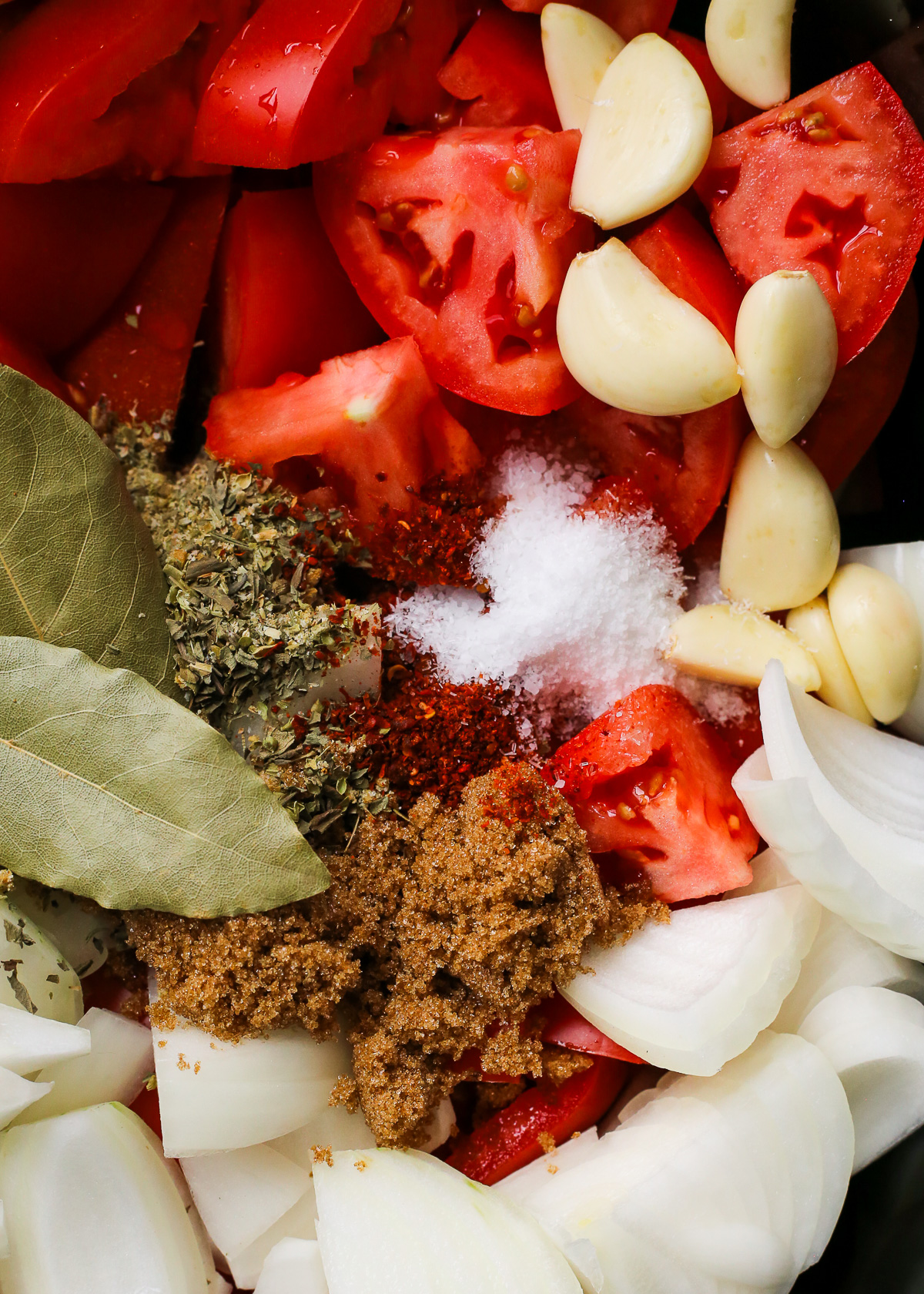 A close-up view of all ingredients needed to make a homemade marinara sauce recipe in the bowl of a slow cooker.