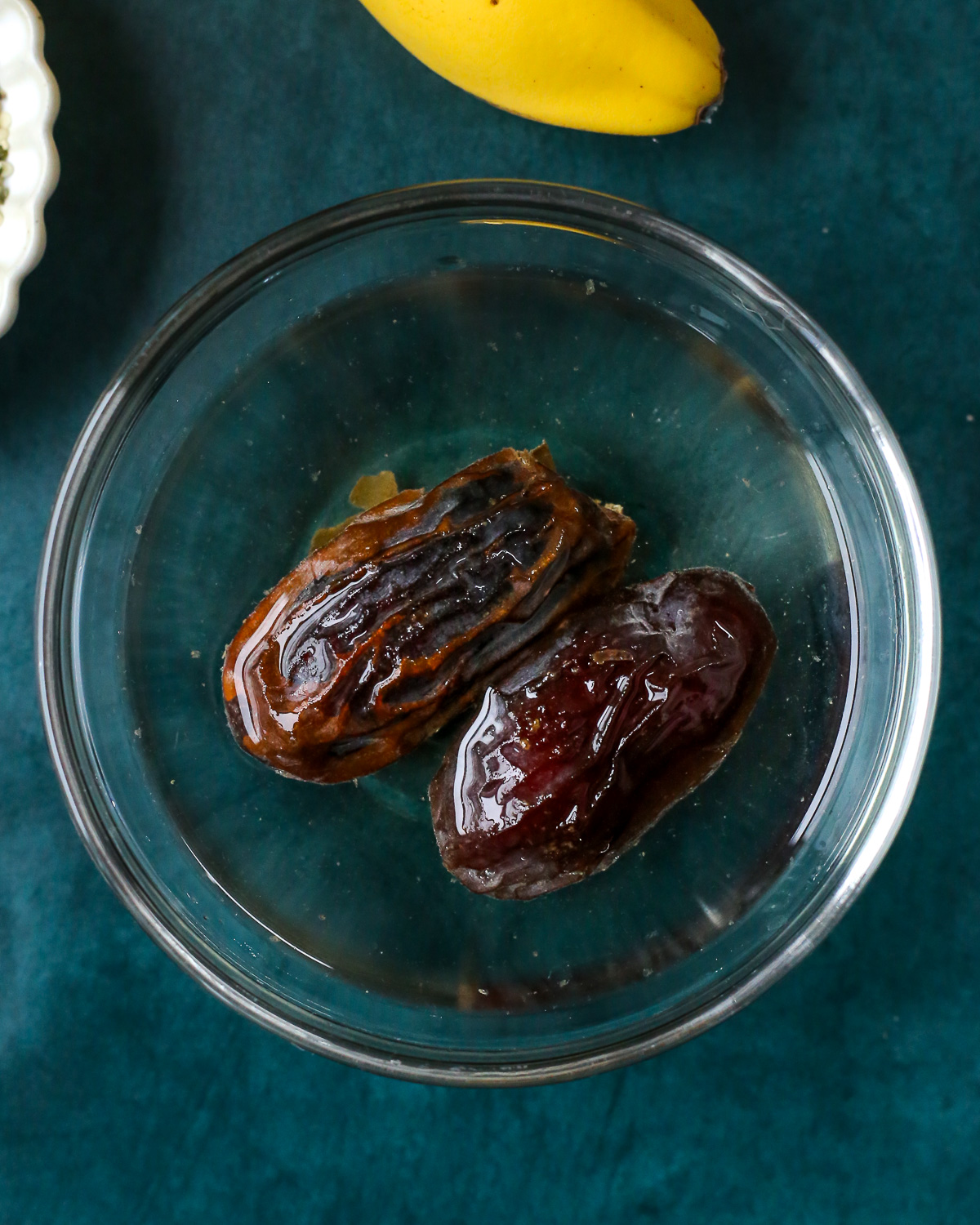 Two pitted Medjool dates in a small bowl of warm water. 