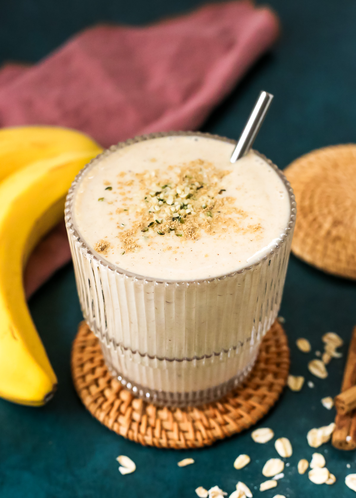 A glass filled with a creamy smoothie made with bananas, dates, oats, and oatmilk. 