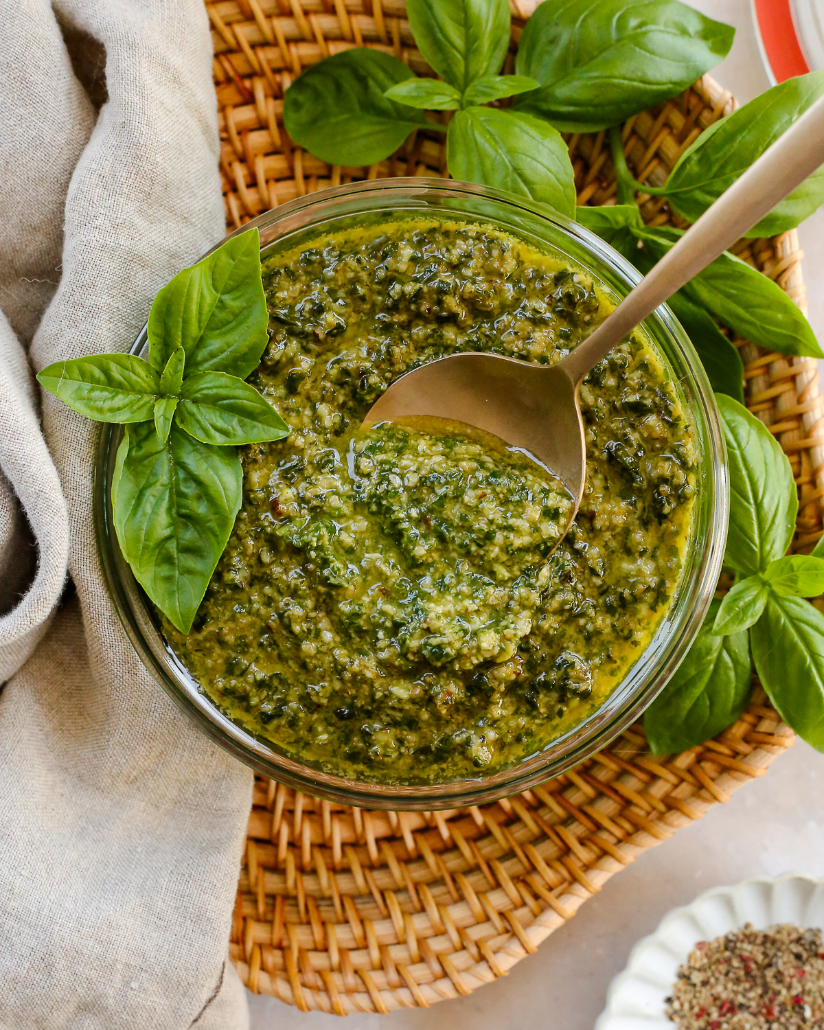 Overhead view of a glass bowl filled with a homemade pesto sauce, garnished with fresh basil. 