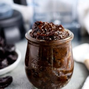 Small glass jar of Easy Prune Puree with blender in the background
