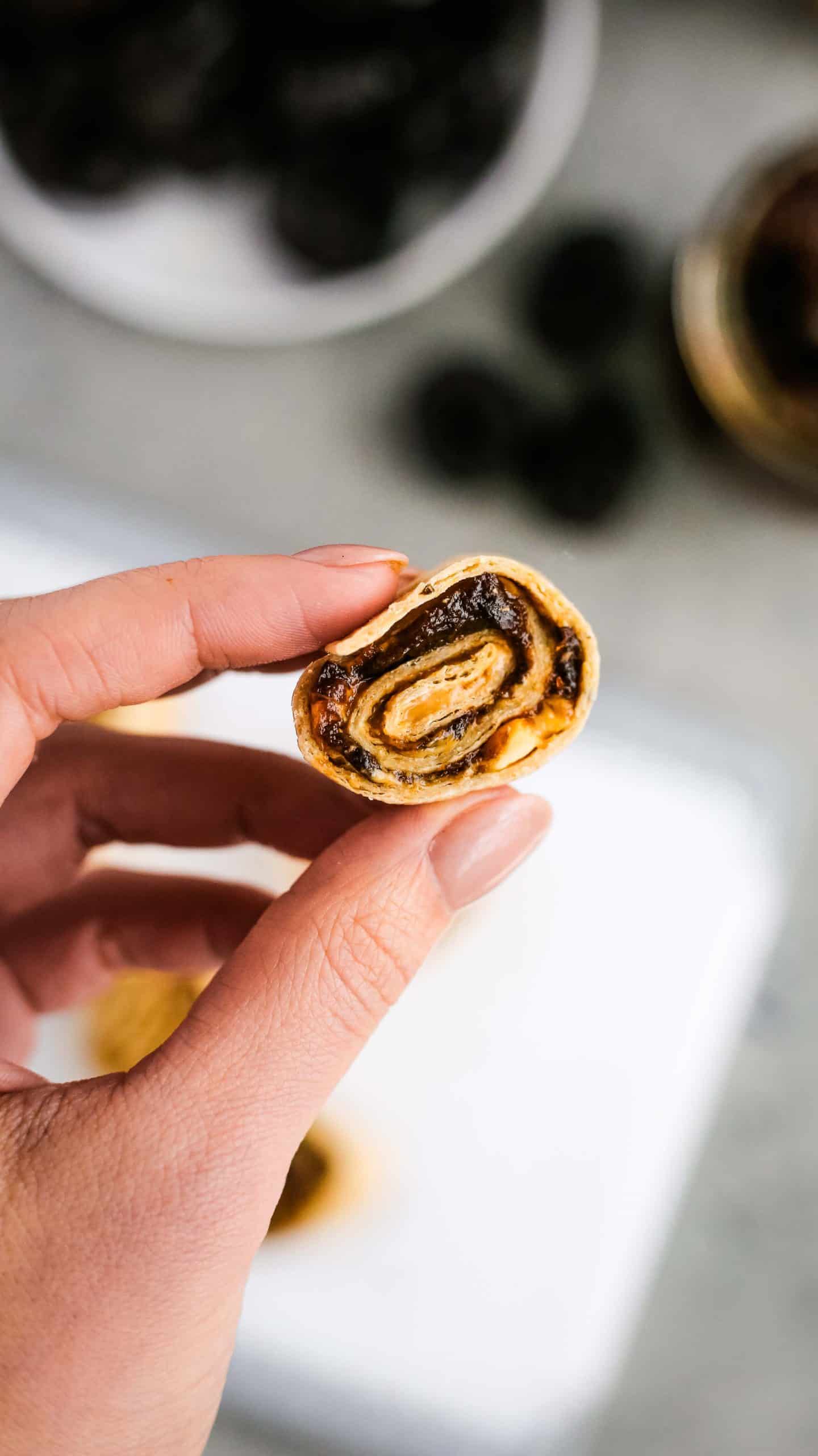 A woman's hand holding a rollup made with an easy prune puree to help enjoy the health benefits of prunes