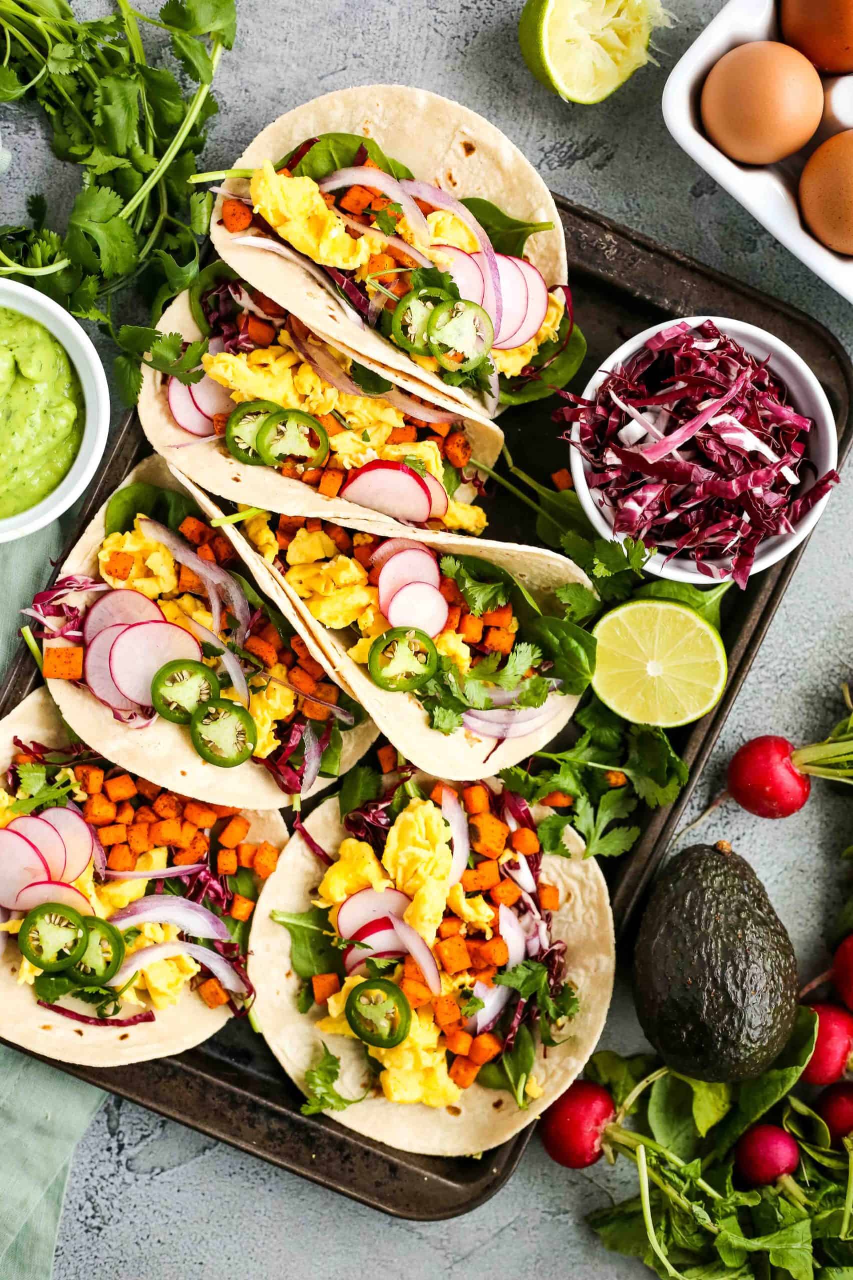 Breakfast tacos on a sheet pan with scrambled eggs, spring veggies, and extra cilantro