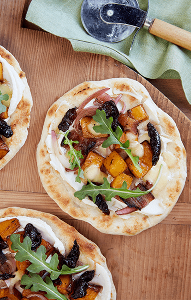 A small flatbread with prunes, butternut squash, and arugula