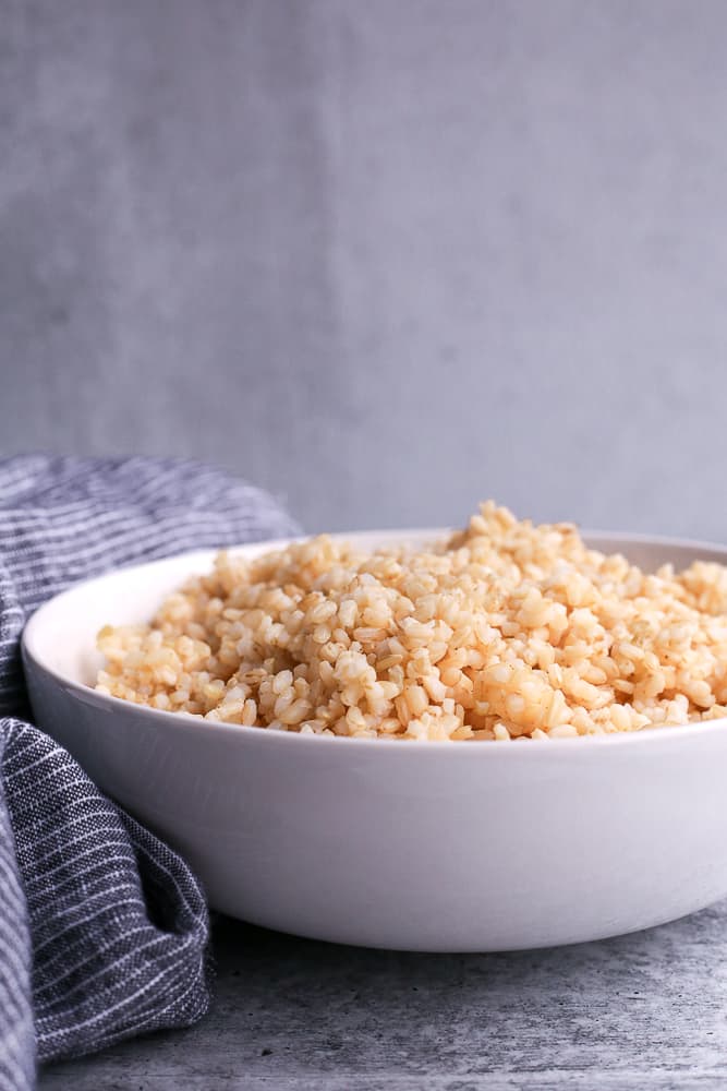 Image of brown rice cooked on the stove top in a white serving bowl
