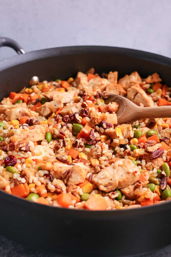 Brown rice and sweet potato skillet with a wooden serving spoon