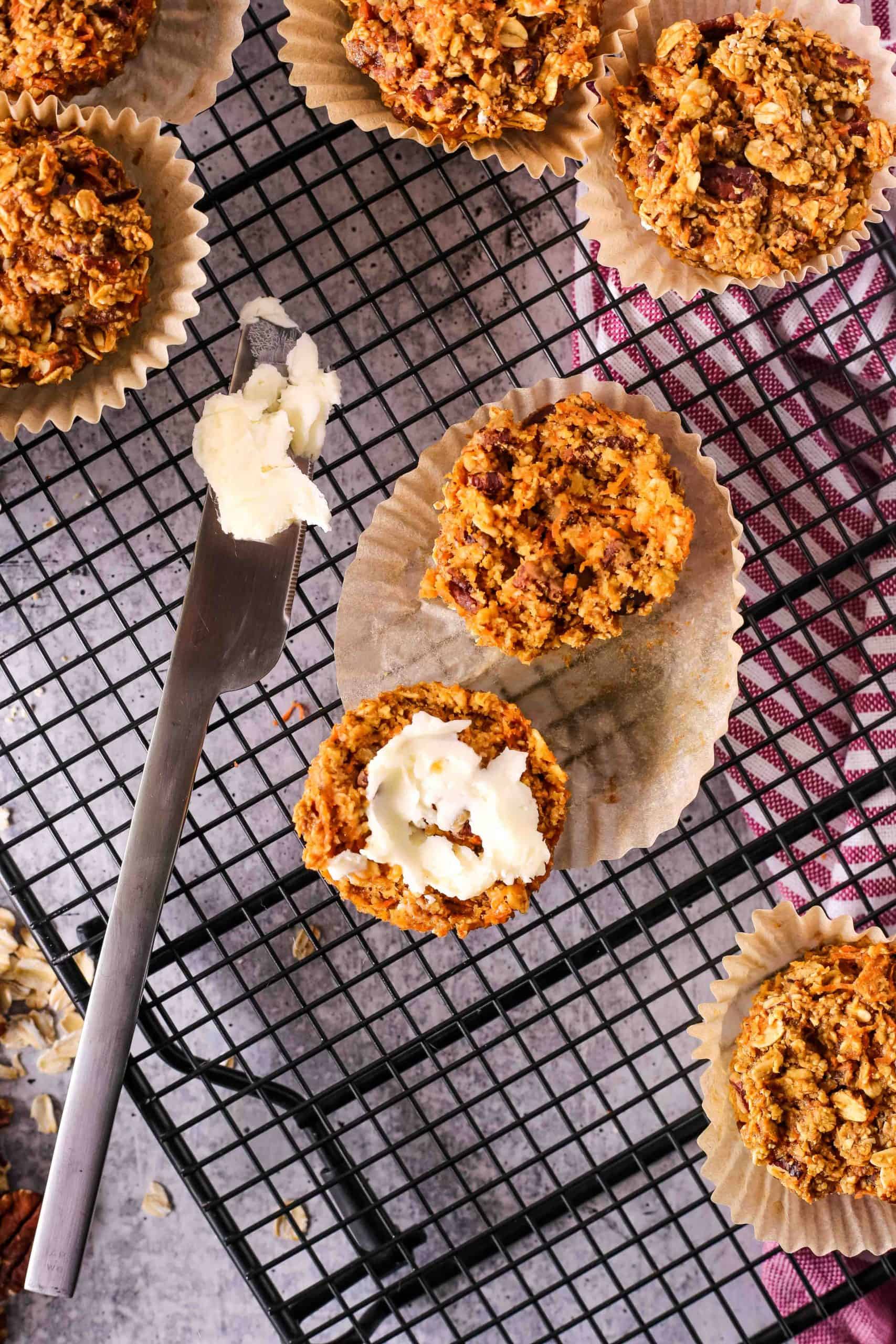 Overhead view of a baked oat muffin with a pat of butter on a cooling rack