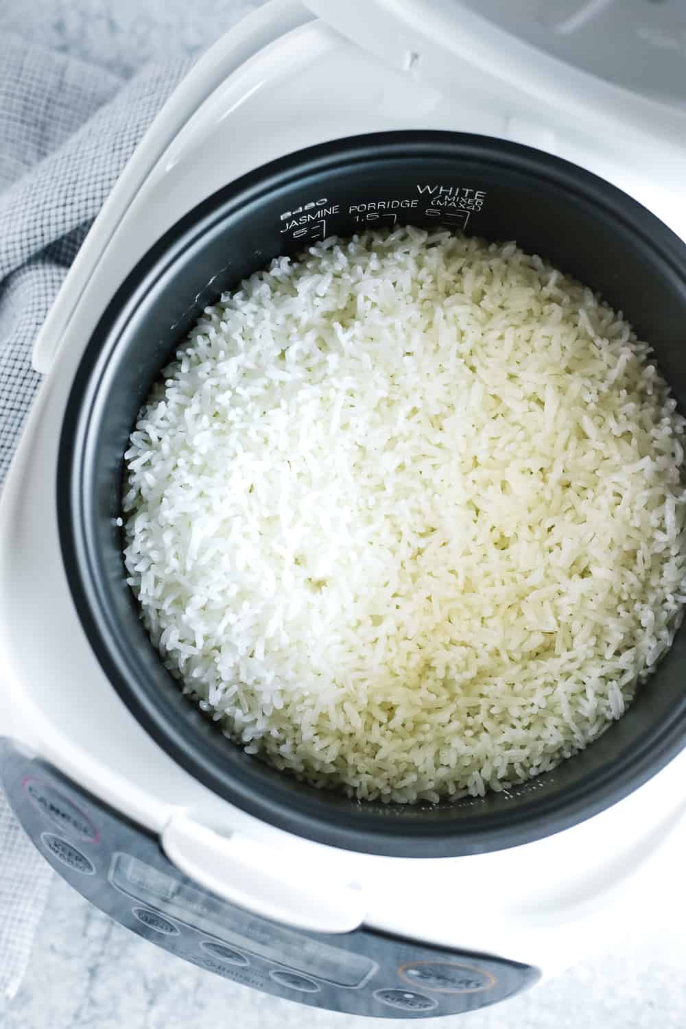 Overhead view of the inside of a rice cooker with cooked white rice