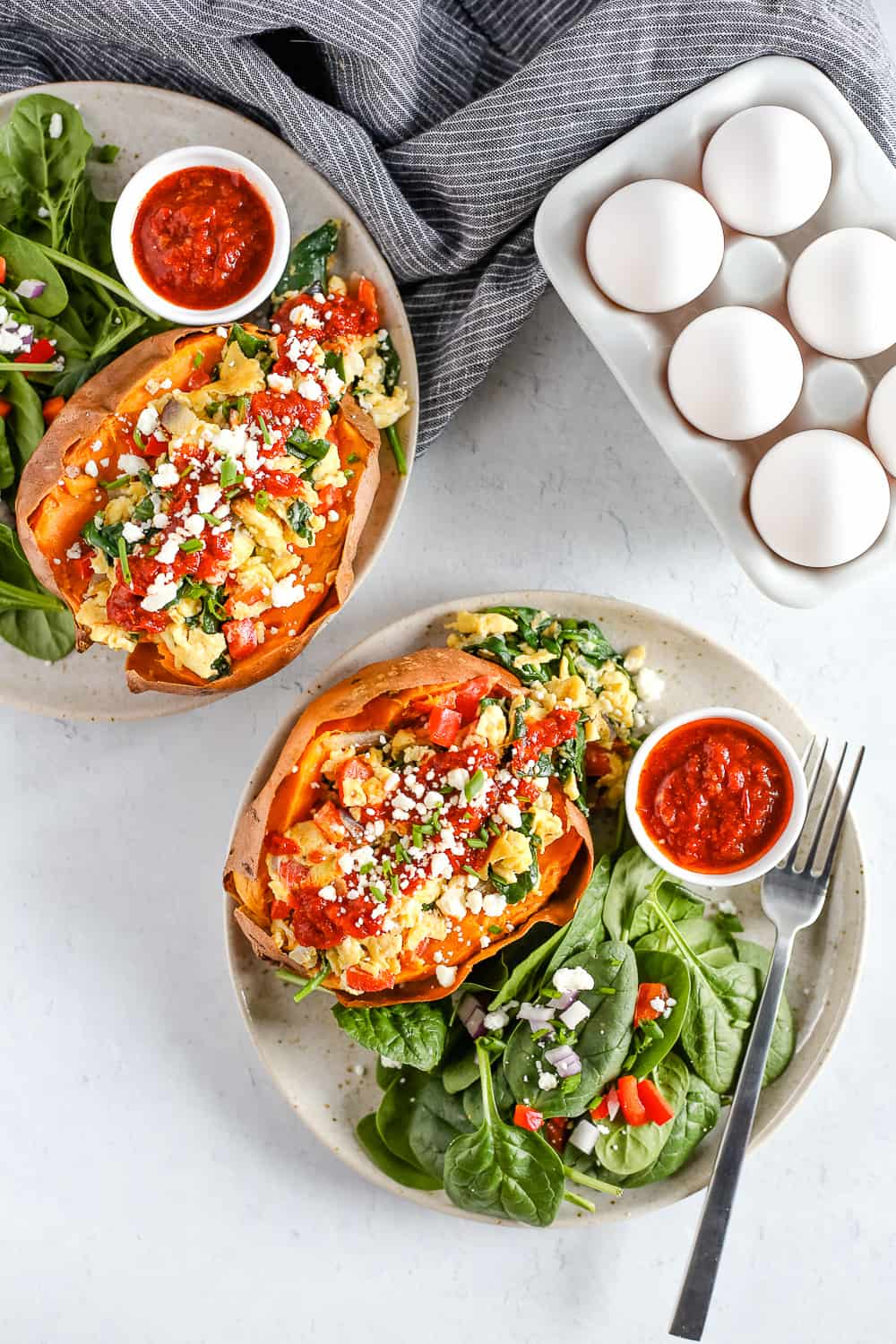 Overhead view of two plates with breakfast stuffed sweet potatoes served with a side salad