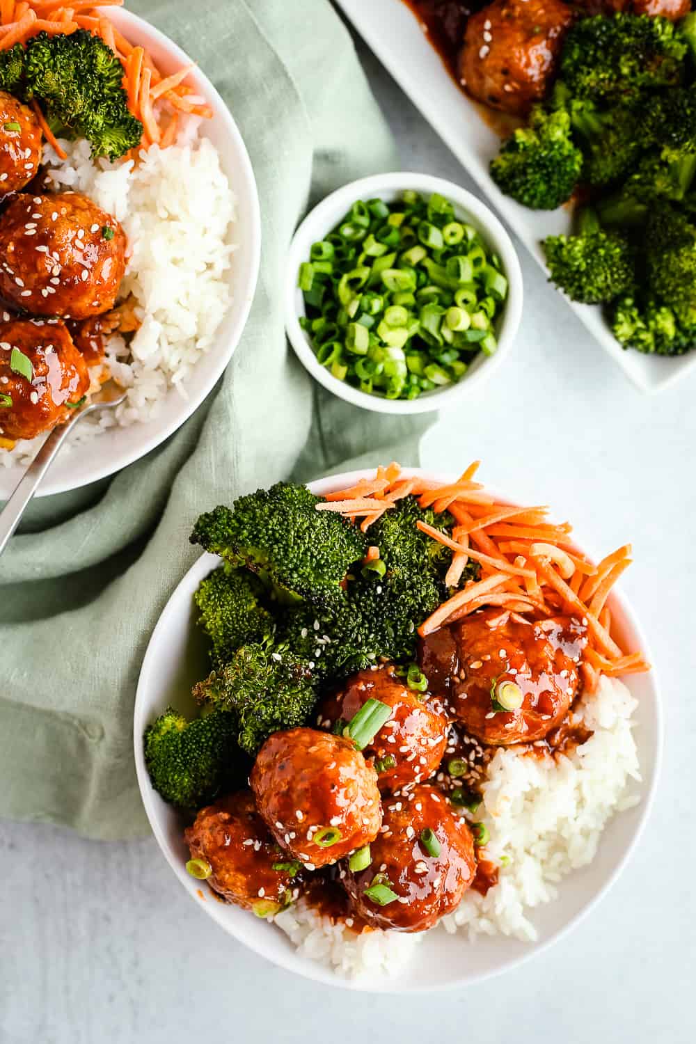 An overhead view of a spicy turkey meatball recipe in the form of rice bowls with roasted broccoli, carrots, and sweet and spicy turkey meatballs