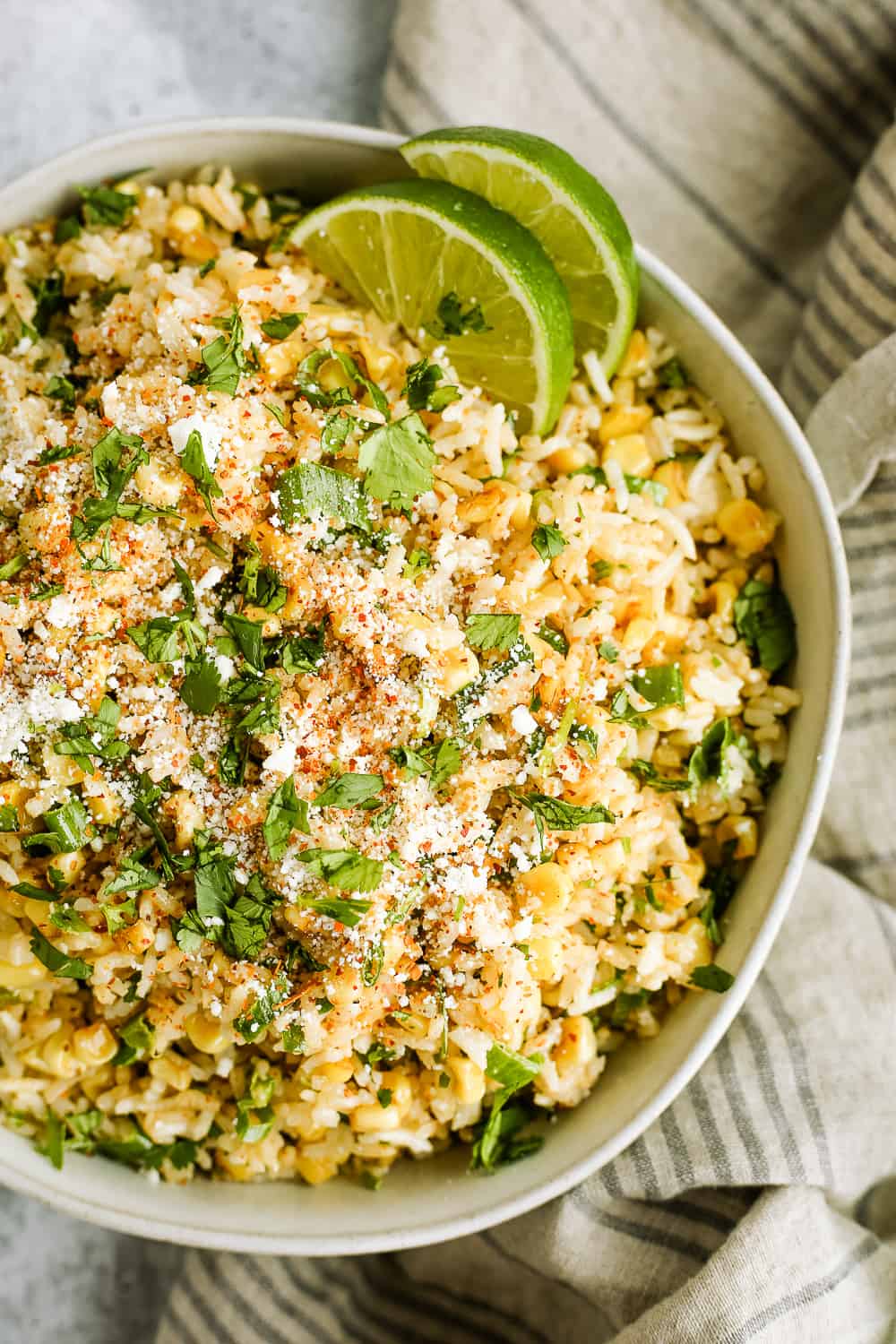 Overhead view of esquires-inspired Mexican street corn and rice bowls, garnished with cilantro and lime wedges