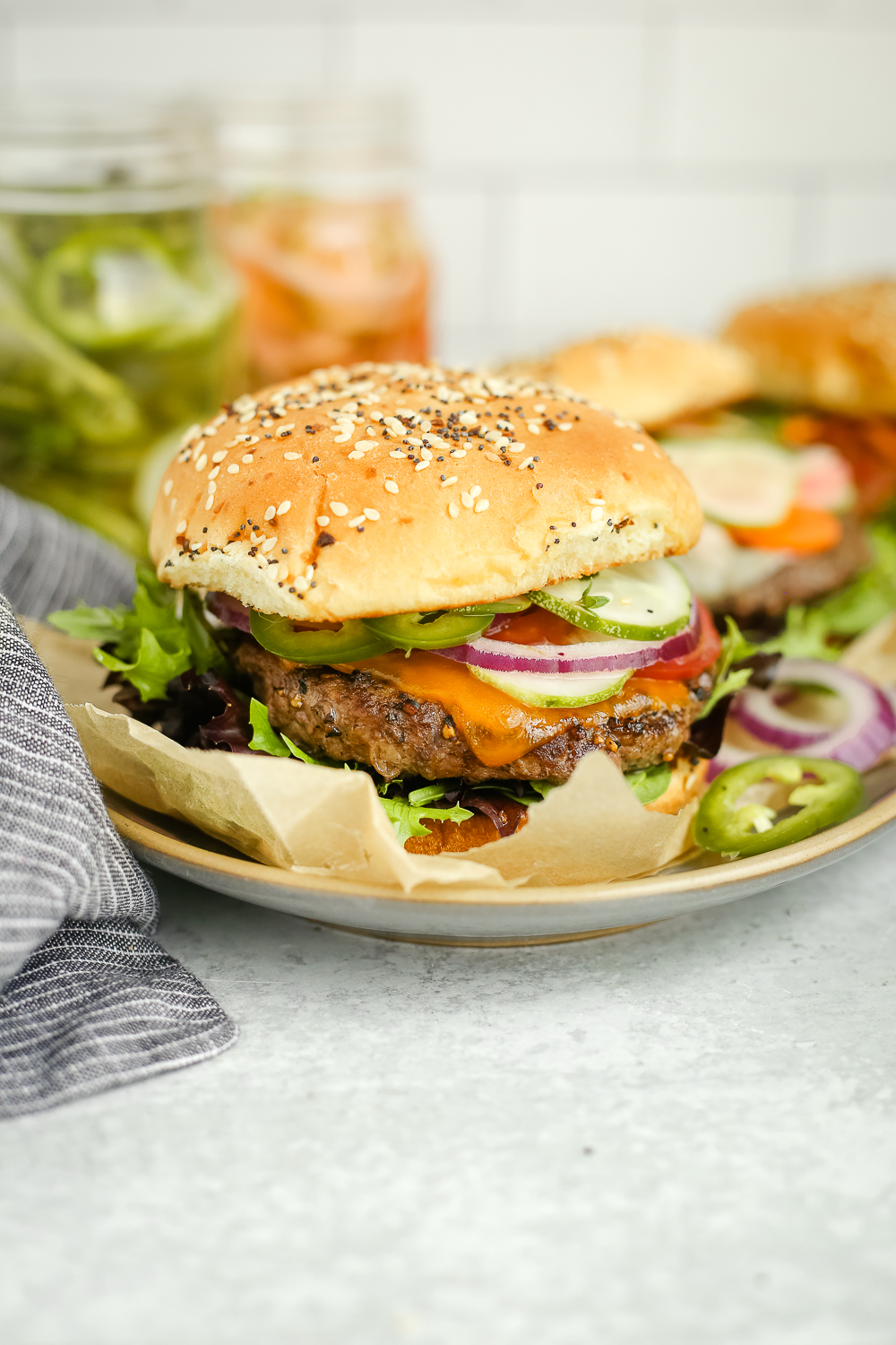 Side view of a beef burger with traditional toppings on a toasted bun and served on a small white dish on a kitchen countertop