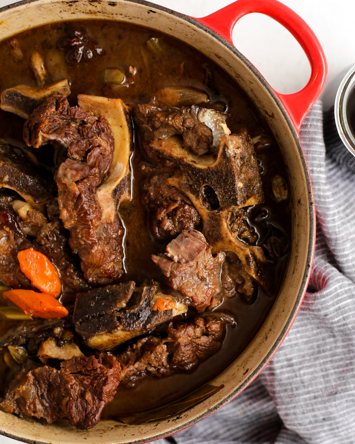 Overhead view of braised beef neck bones in a red dutch oven