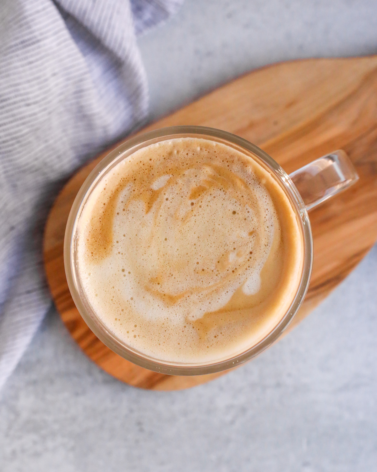Overhead view of an olive oil latte in a clear glass mug, showing a creamy and luxuriously smooth texture 