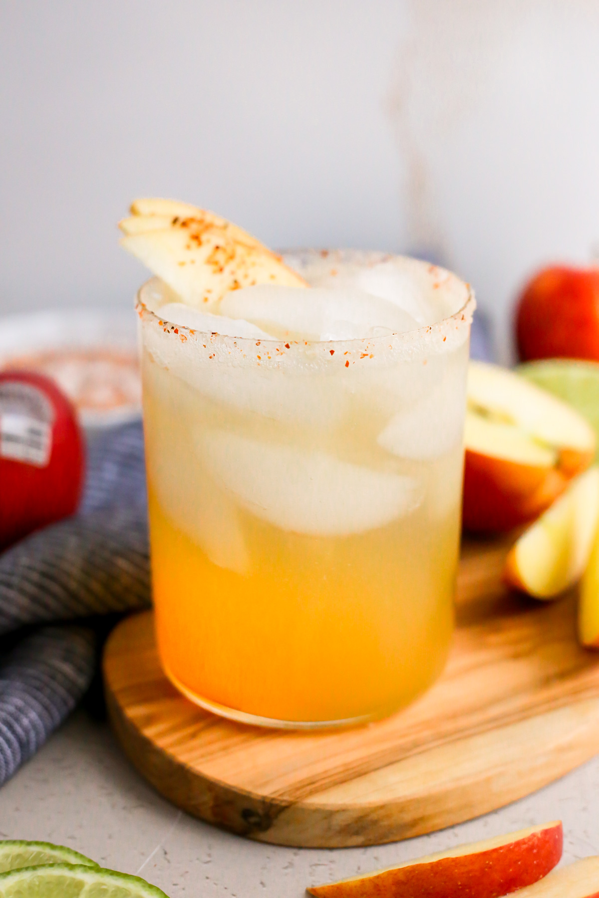 An apple margarita mocktail is displayed on a wooden serving tray on a kitchen countertop