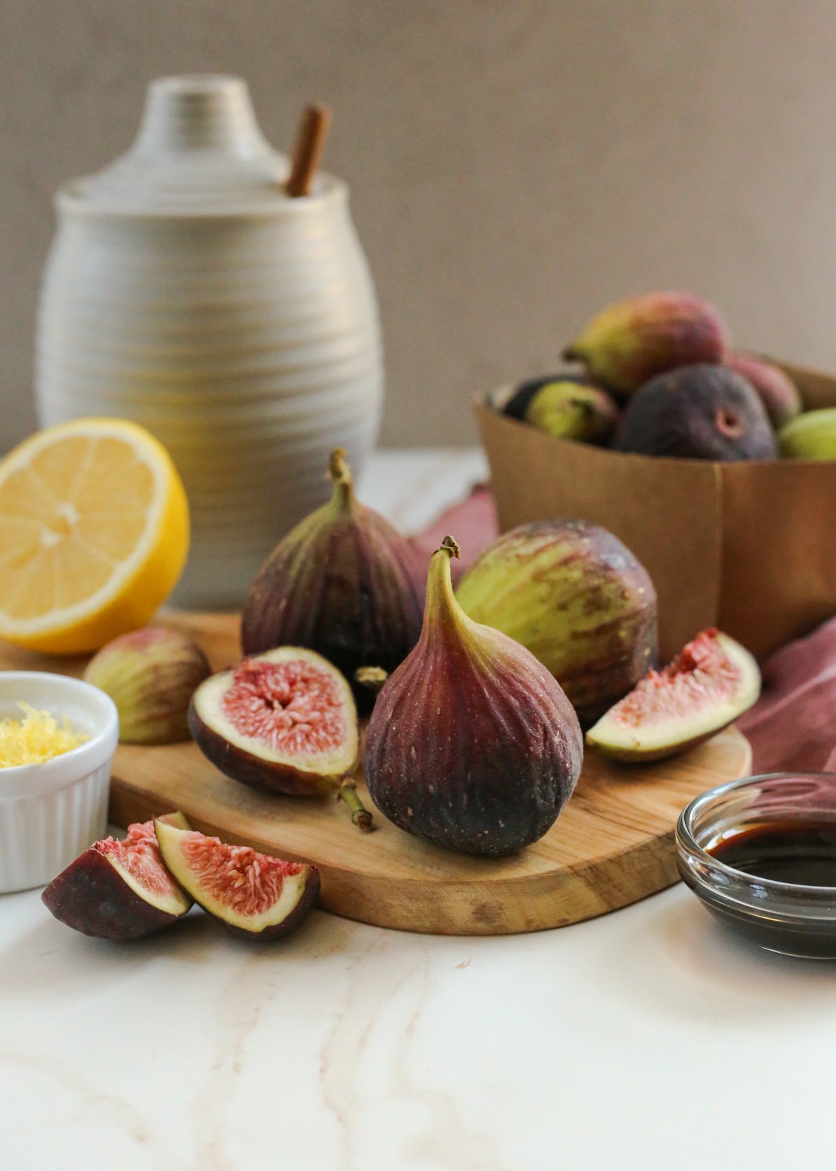 Brown turkey figs are displayed in a kitchen scene, with some of the figs sliced open to reveal the seeds and colorful interior