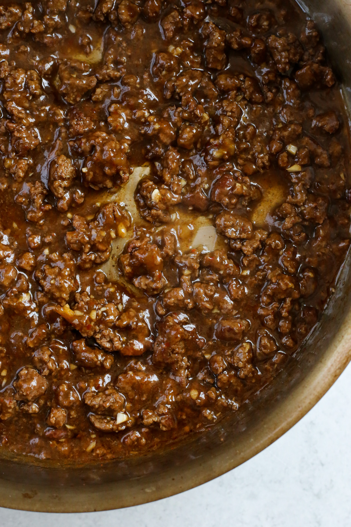 Cooked ground beef coated in a savory sauce.