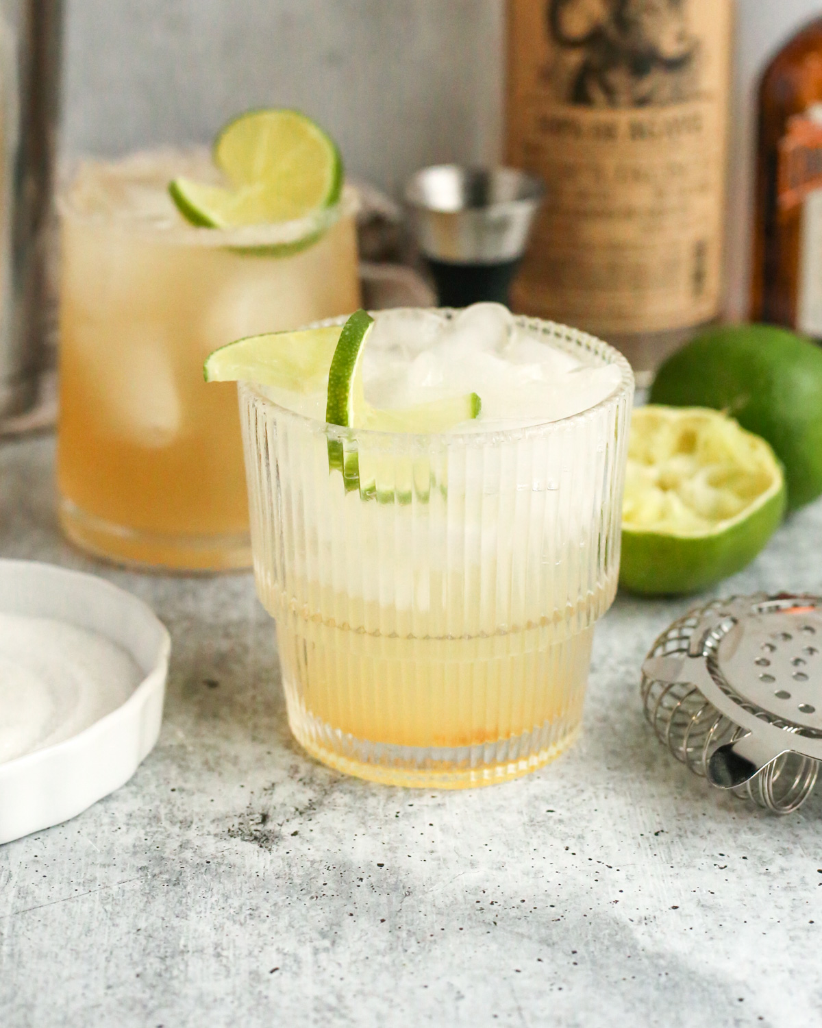 A yuzu margarita mocktail served in a cocktail glass and garnished with a lime wheel