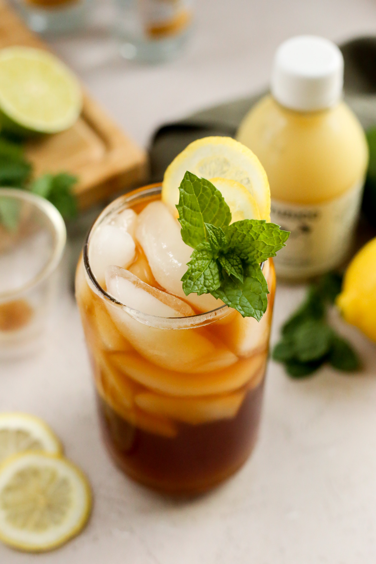 Overhead view of a yuzu espresso tonic in a clear glass with many ice cubes, showing lemon wheels and a sprig of fresh mint as garnish