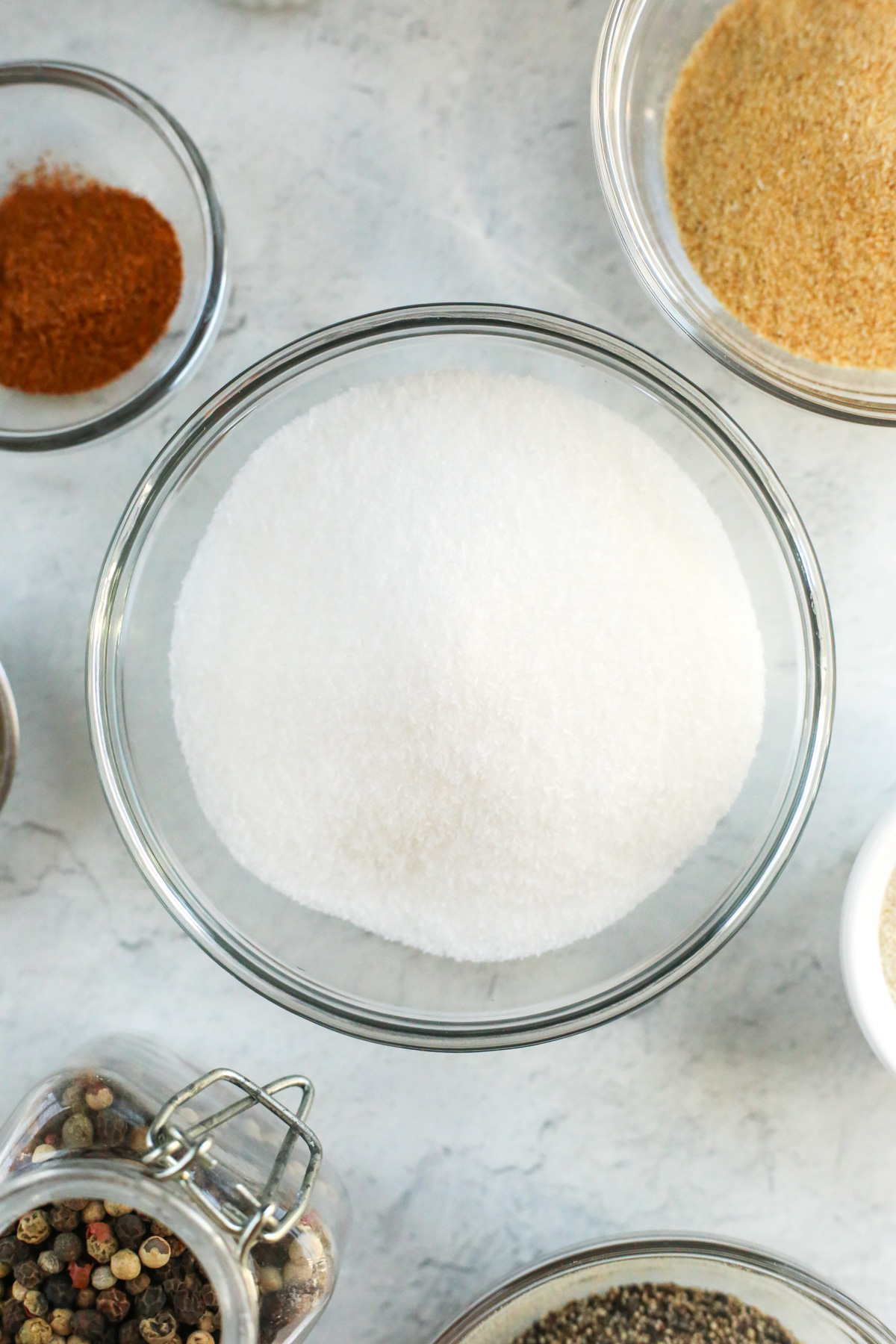 Overhead view of a small glass prep bowl filled with MSG, which appears as a fine white powder