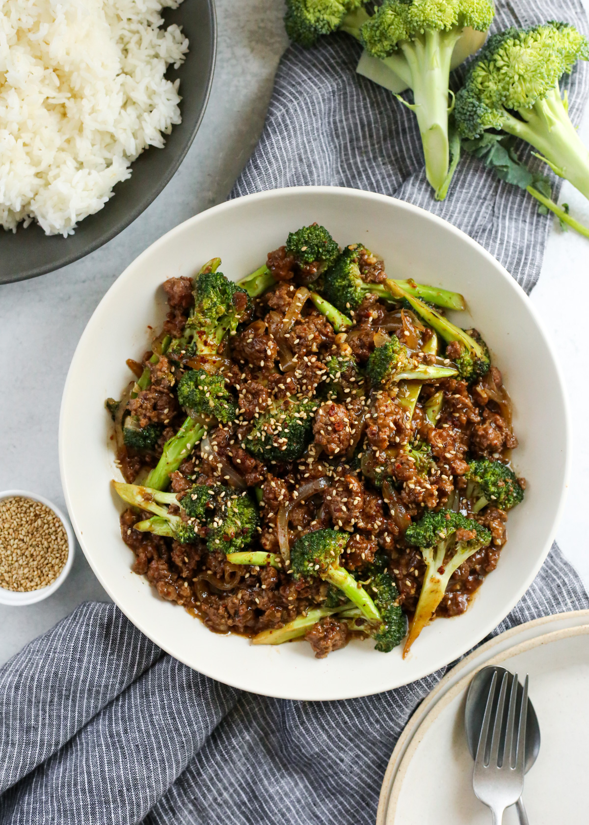 Overhead view of a serving bowl filled with ground beef and broccoli covered in a savory gravy-like sauce and garnished with toasted sesame seeds