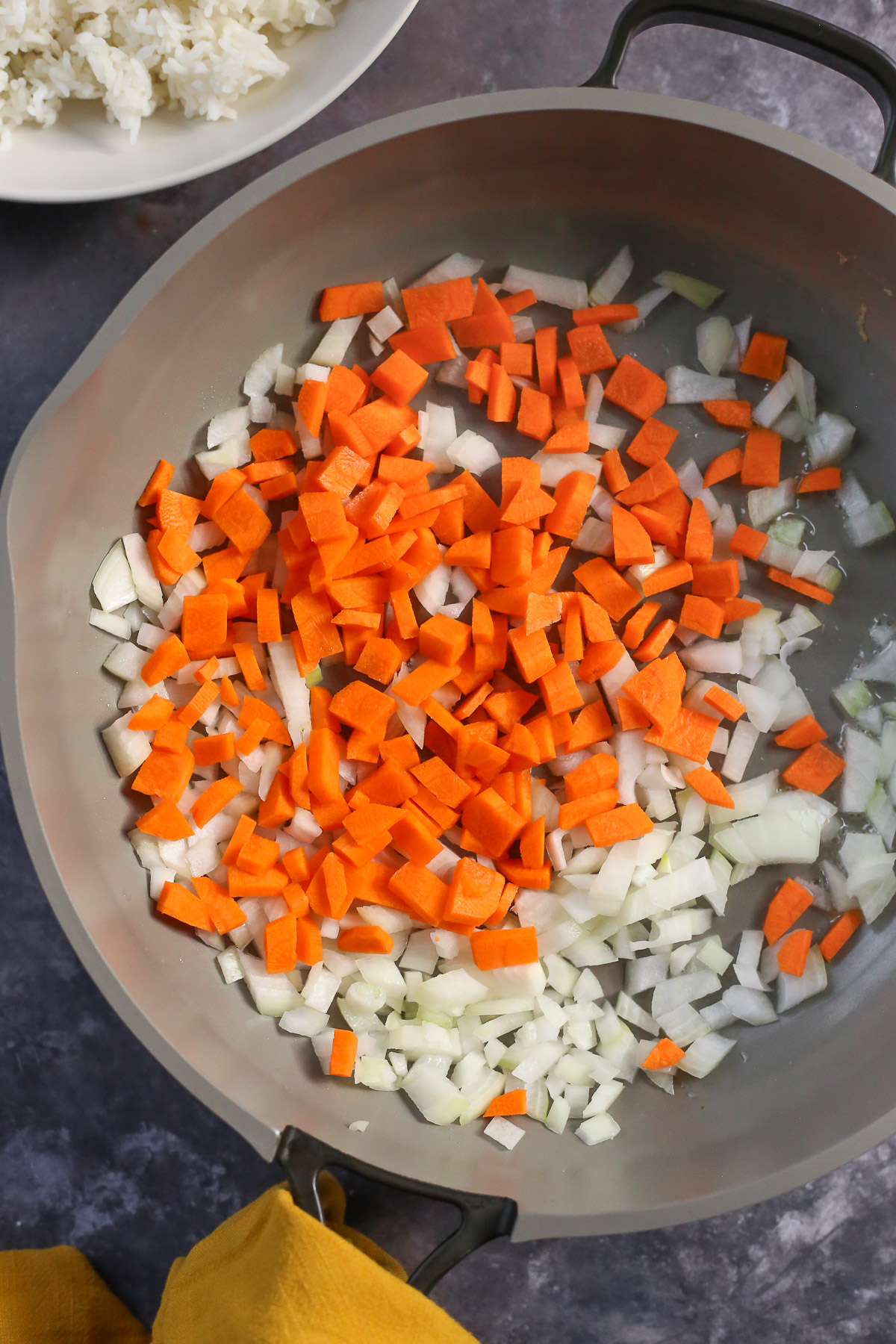 A large nonstick skillet with diced onions and carrots.