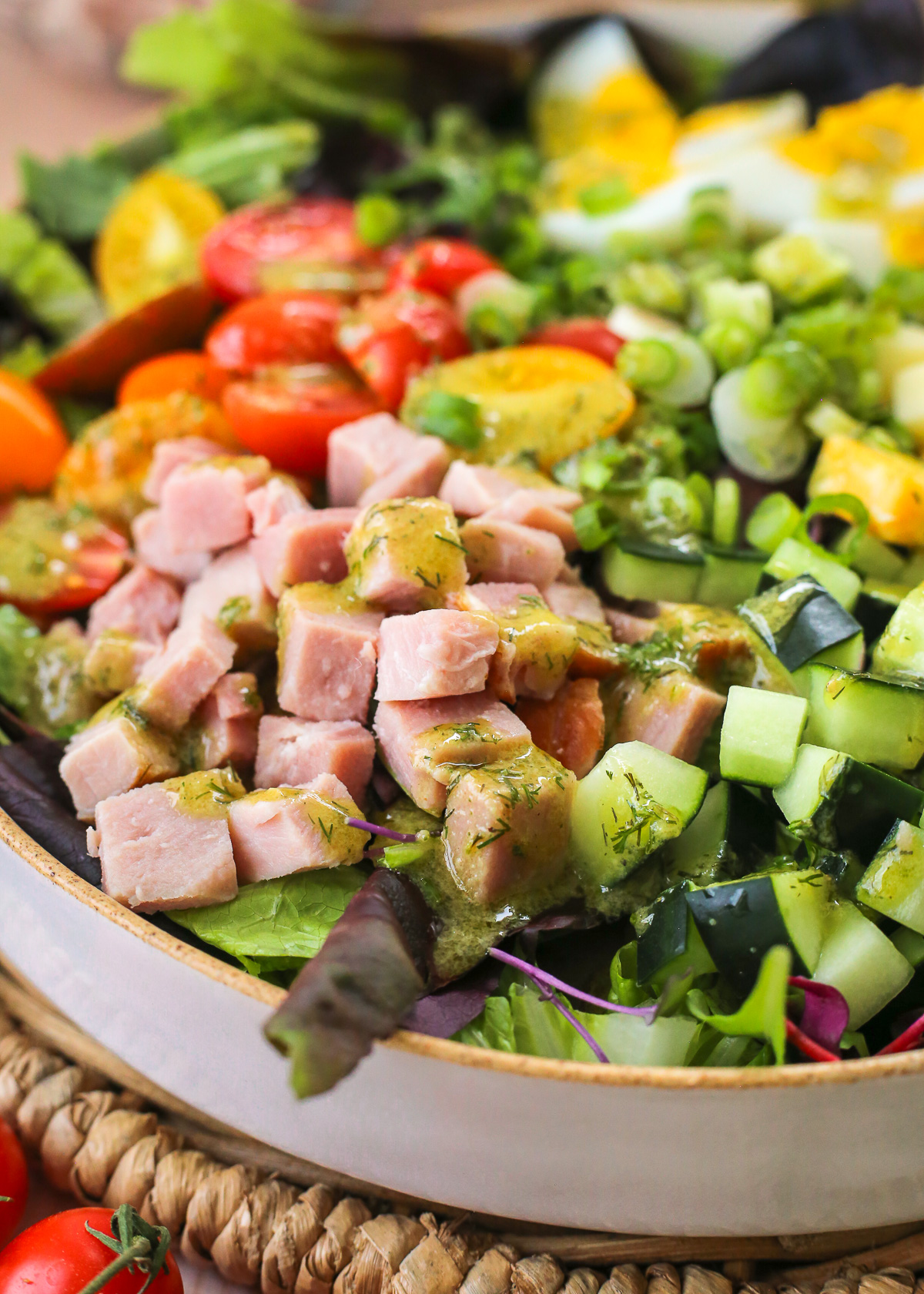 A large chefs salad made with ham, cheese, cucumbers, tomatoes, hard boiled eggs, and chopped salad greens drizzled with a homemade ranch vinaigrette dressing.