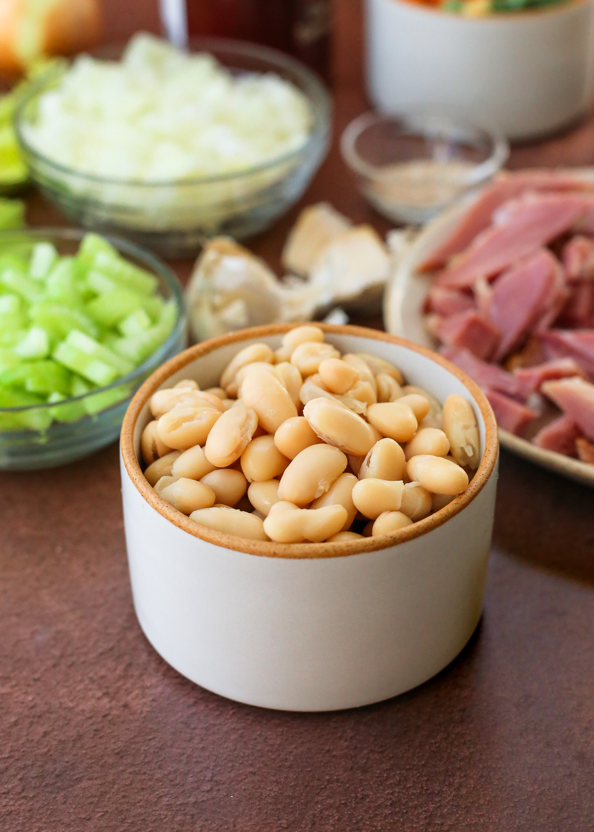 A close up image of a small ceramic ramekin full of cooked white beans.