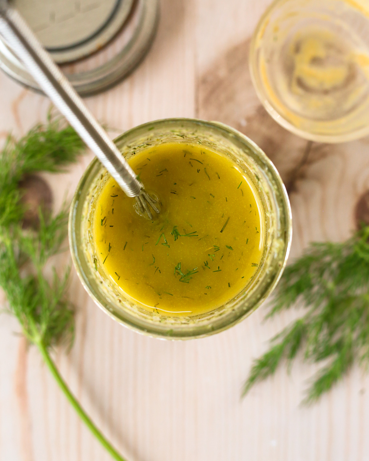 Overhead view of a ranch vinaigrette recipe, mixed in a small mason jar, with sprigs of fresh dill surrounding it.