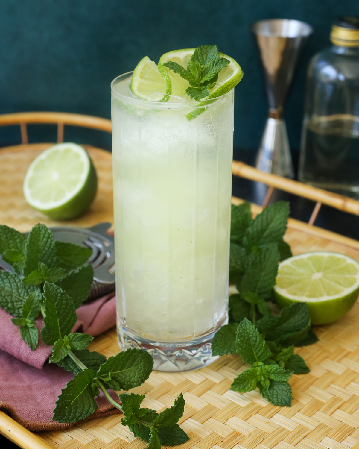 A highball glass filled to the brim with a yuzu mojito, garnished with fresh mint and a twist of lime. 