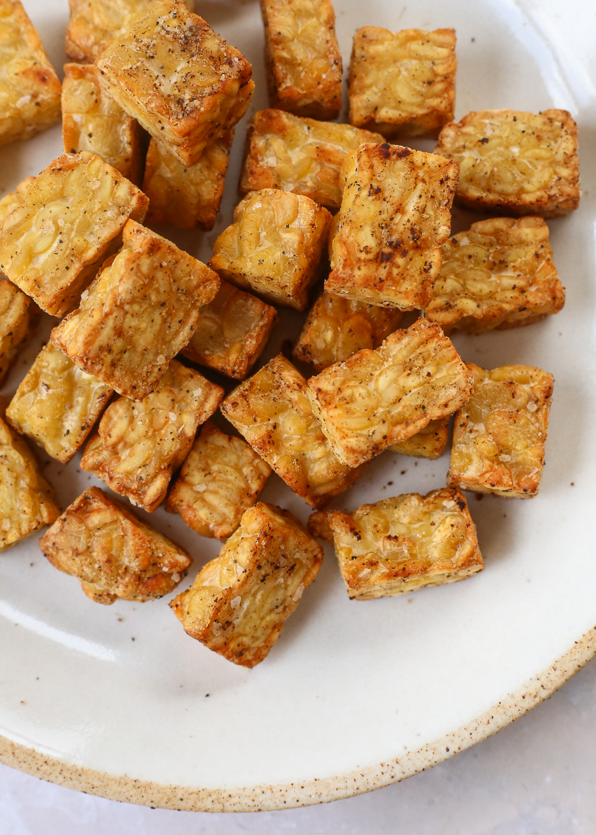 Detail shot of crispy air fryer tempeh after cooking, with the cubed tempeh appearing golden brown and well-seasoned.