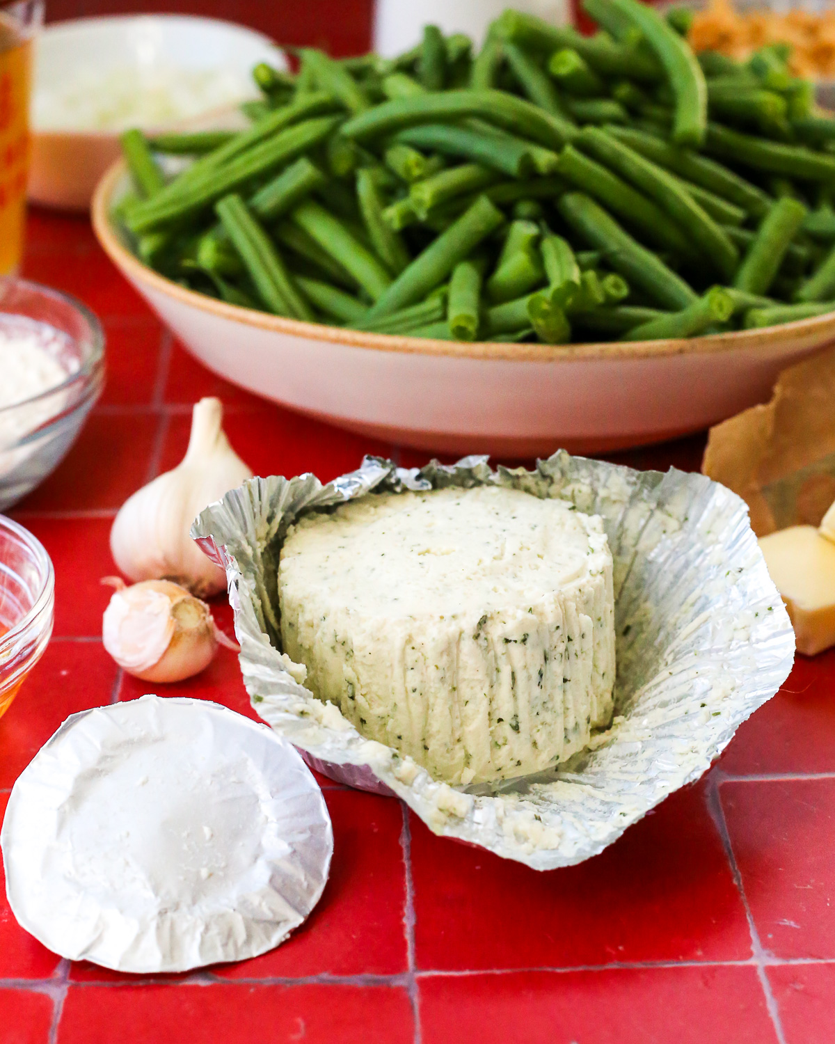 An open wheel of Boursin cheese, showing the flecks of garlic and herbs inside a creamy, soft cheese.