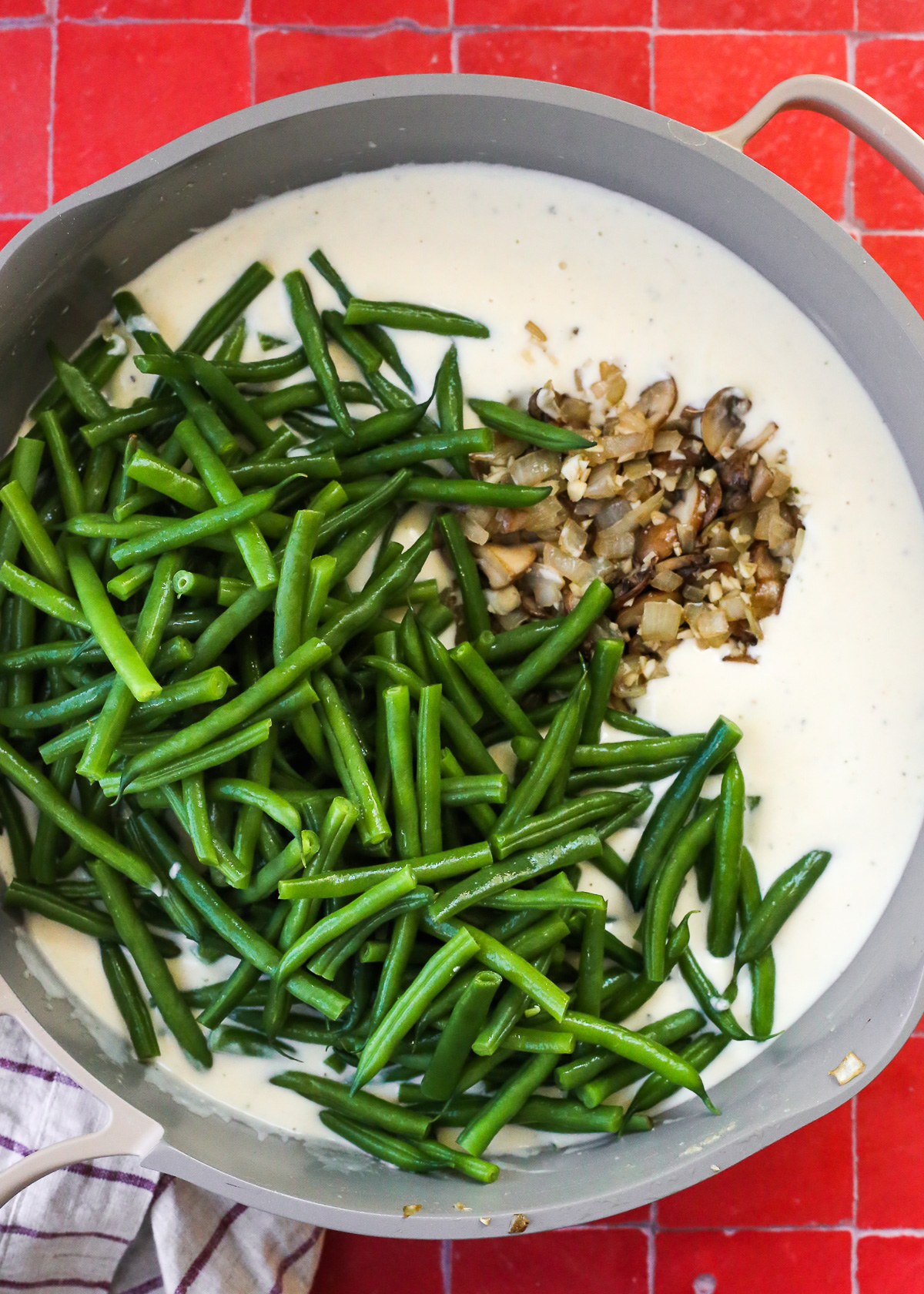 A creamy bechamel sauce, about to be stirred together with blanched green beans for a green bean casserole recipe.
