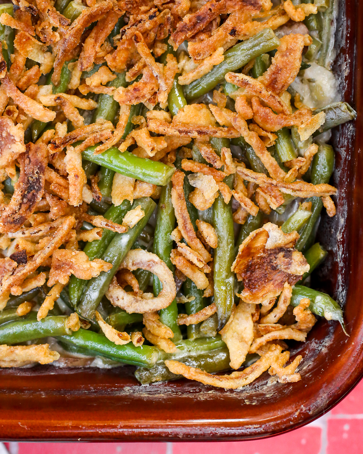 A large baking dish filled with freshly baked green bean casserole and topped with crispy fried onions.