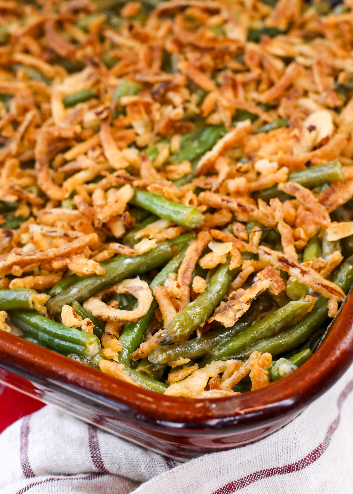 A creamy green bean casserole in a baking dish topped with crispy fried onions.