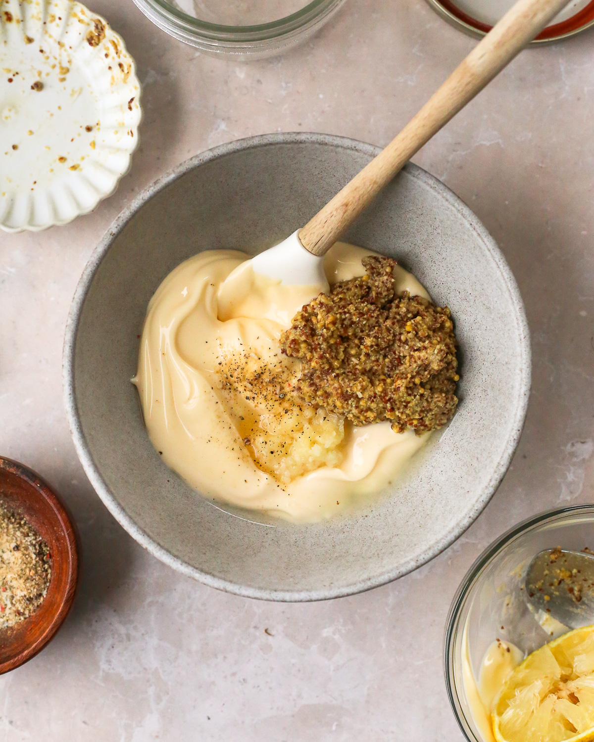 A small mixing bowl with mayonnaise, grated garlic, and dijon mustard (unmixed).