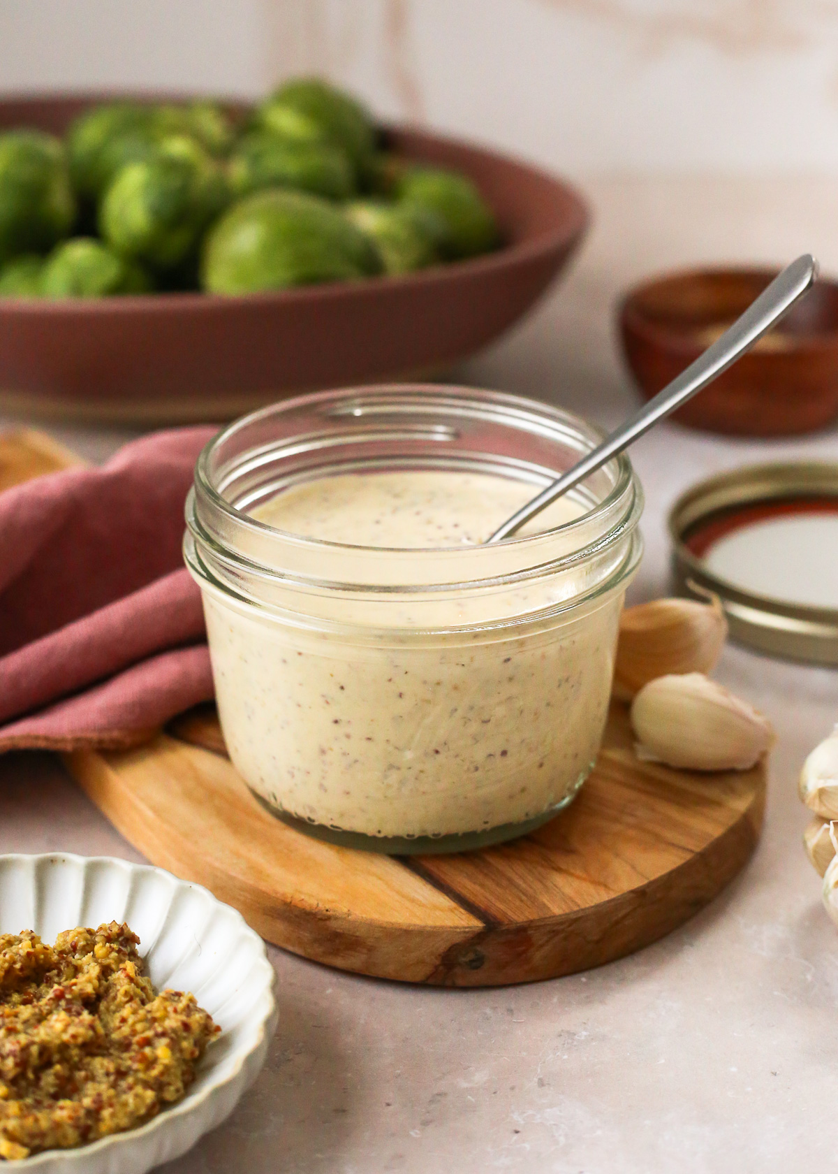 A small glass jar filled with a dijon aioli sauce, displayed on a kitchen countertop. 