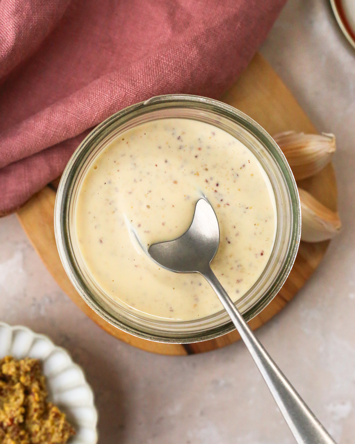 Overhead view into a glass mason jar containing a homemade dijonnaise sauce with whole grain mustard.