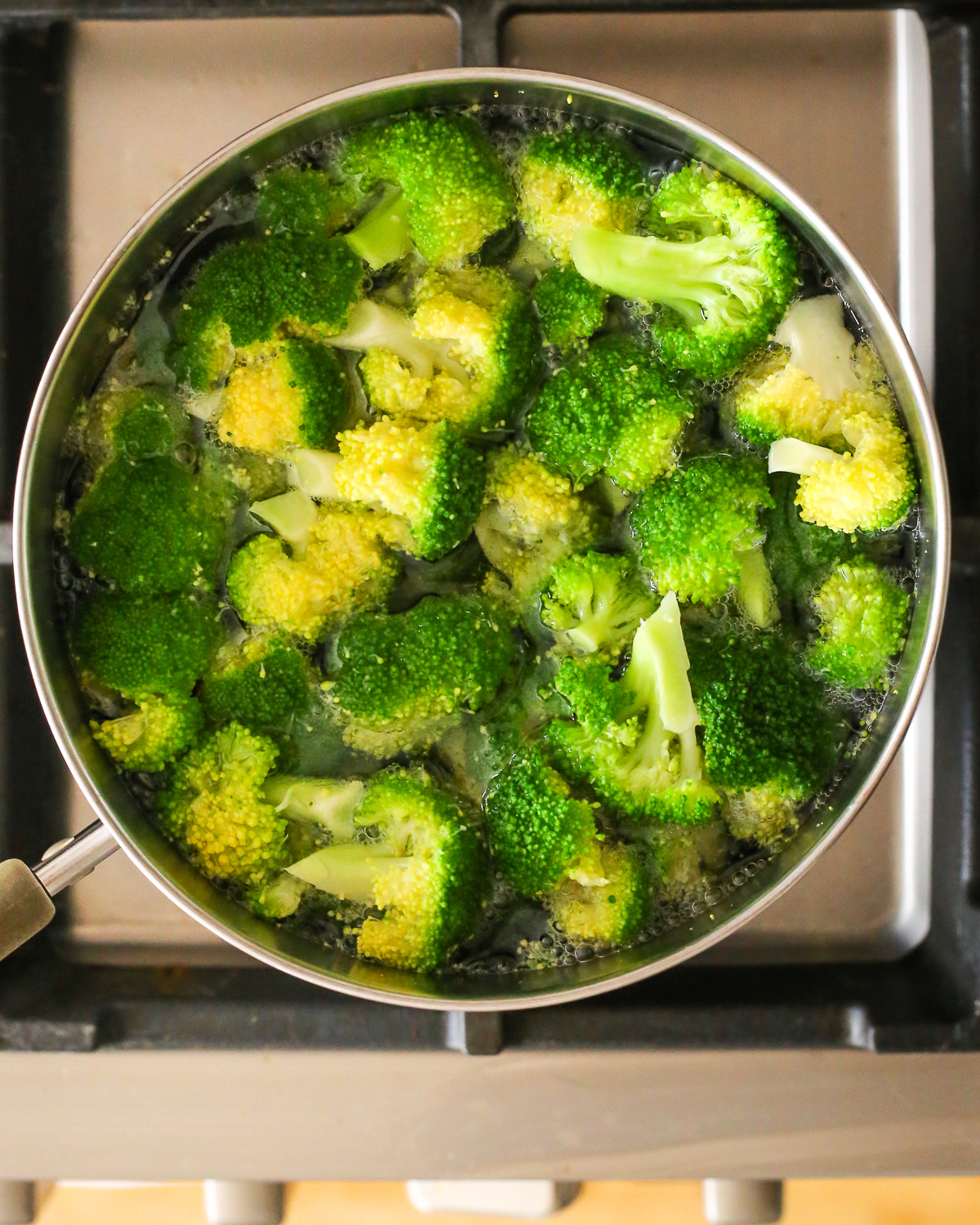 A pot of boiling water on the stovetop, filled with broccoli florets. 