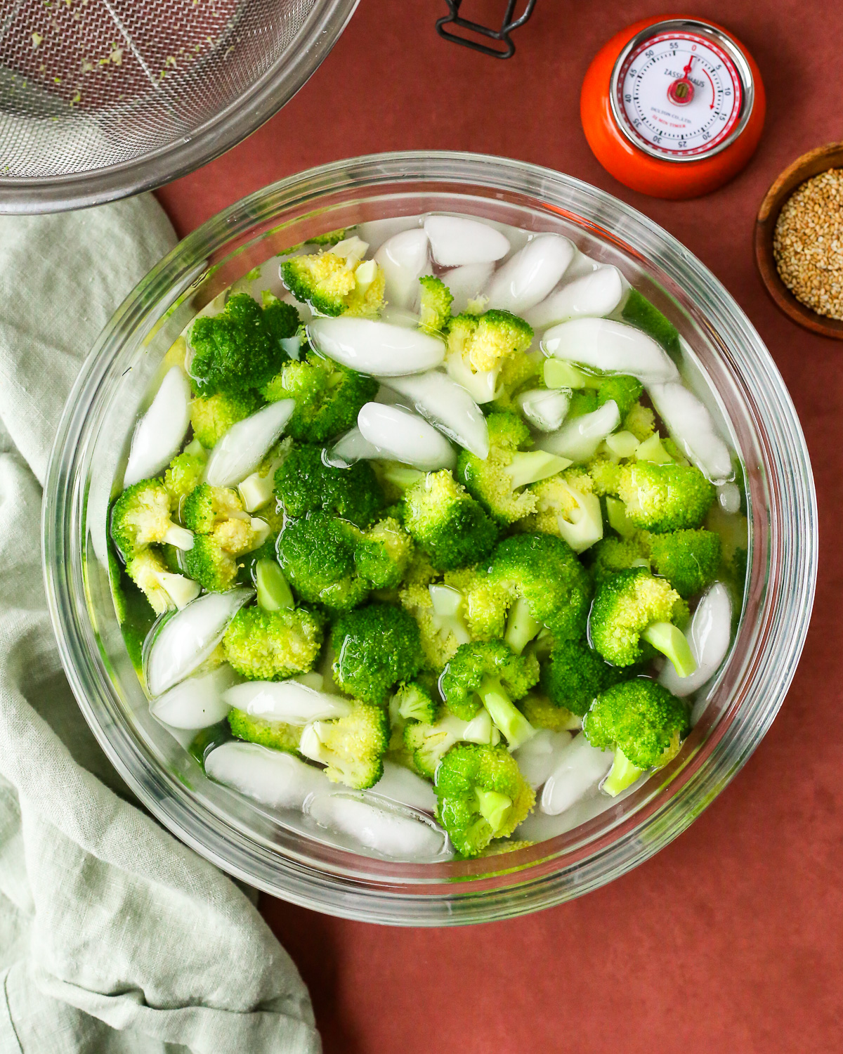 Blanched broccoli florets in a large ice bath.